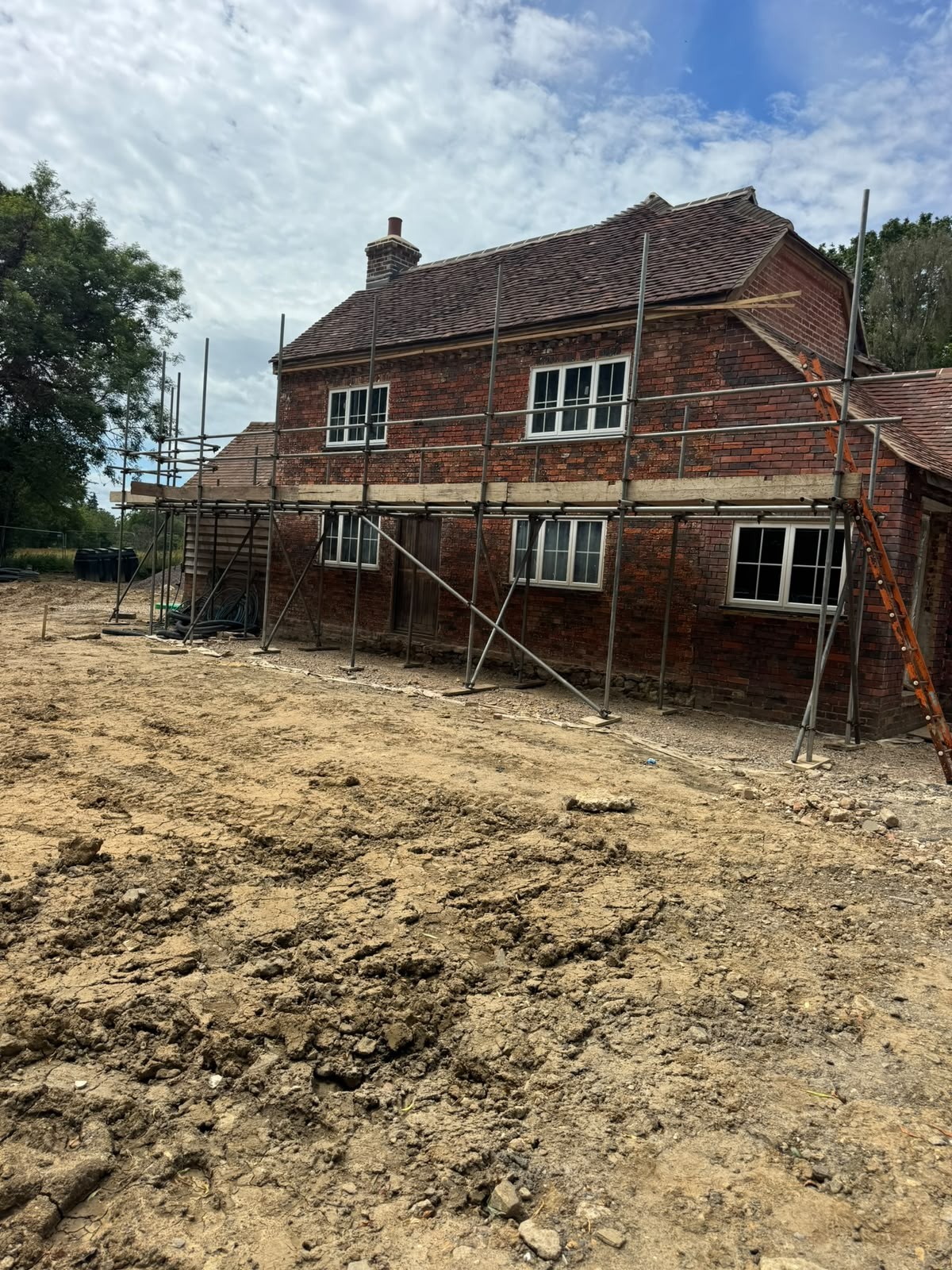 Scaffolding on a period brick farmhouse renovation with base plates on sole boards over soft ground