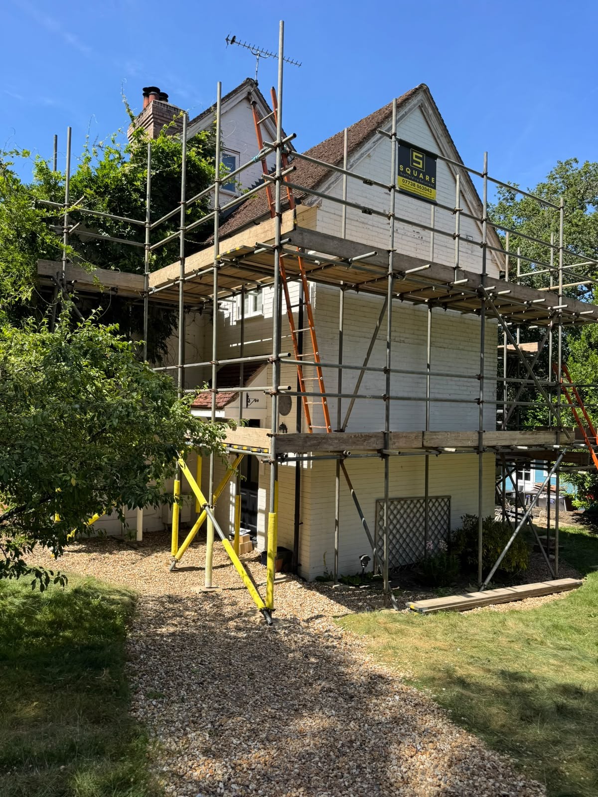 Domestic scaffolding wrapped around a steep pitched roof with ladder access for a re-roof