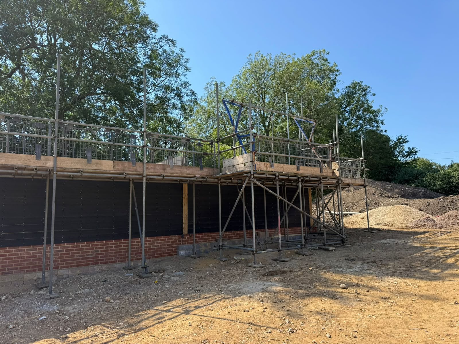 Scaffold framework erected against a clad building elevation on a live construction site