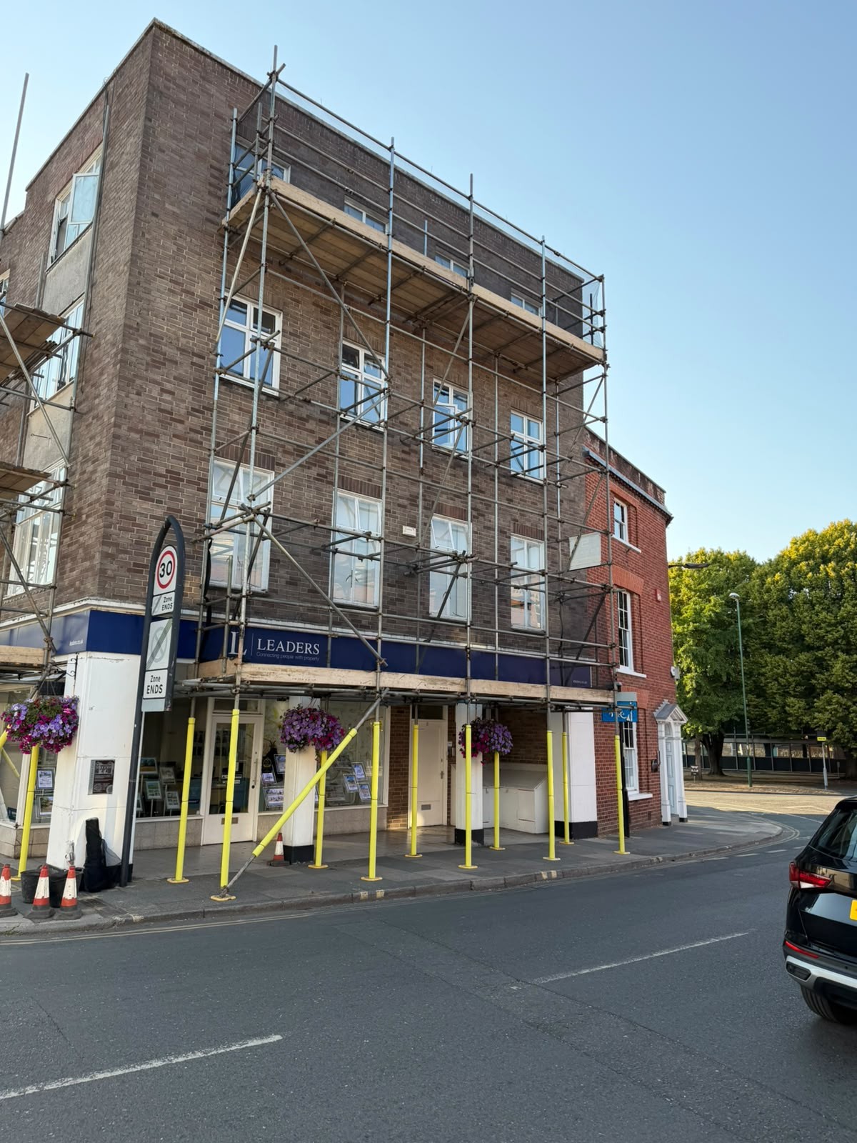 Commercial scaffolding on a high street retail unit with padded standards protecting the shop front